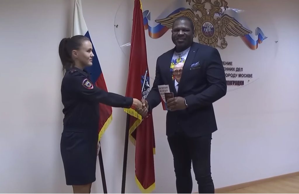 بقميص يحمل صورة بوتين.. الملاكم الأميركي كيفن جونسون يتسلم جواز السفر الروسي